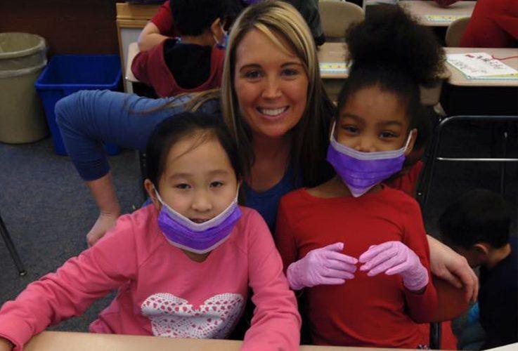 Team member smiling with two young students