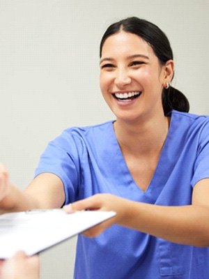 a front desk member handing a form to a patient