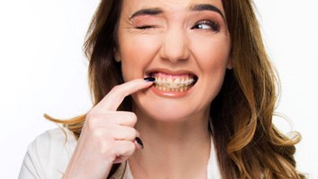 A woman with braces touching her teeth