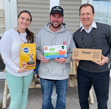 Doctor Drabik and two other people holding dental products outdoors