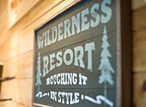Wooden sign saying wilderness resort roughing it in style
