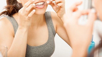 Woman placing whitening strip on her teeth