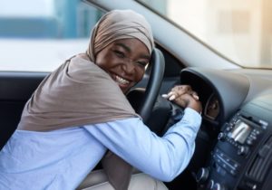 person with braces sitting in the driver's seat of their car going to visit their orthodontist in Rochester