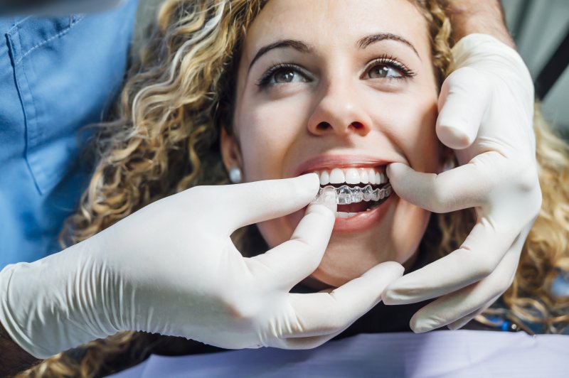 Dentist placing Invisalign in a woman’s mouth