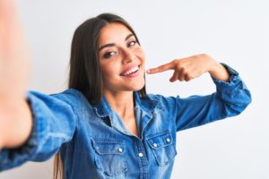 Woman pointing to her straight, beautiful smile