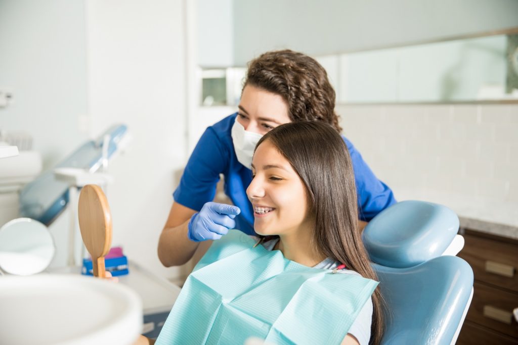 Orthodontist and patient with braces smiling in mirror