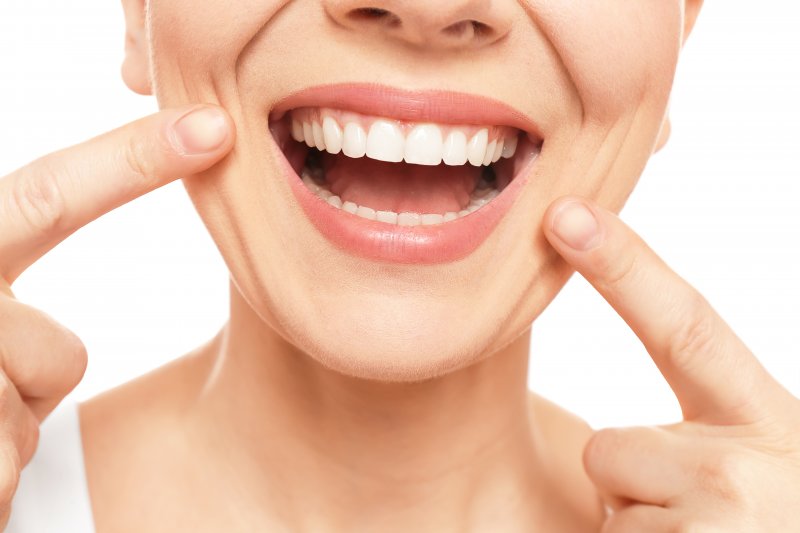 young woman pointing to straight teeth