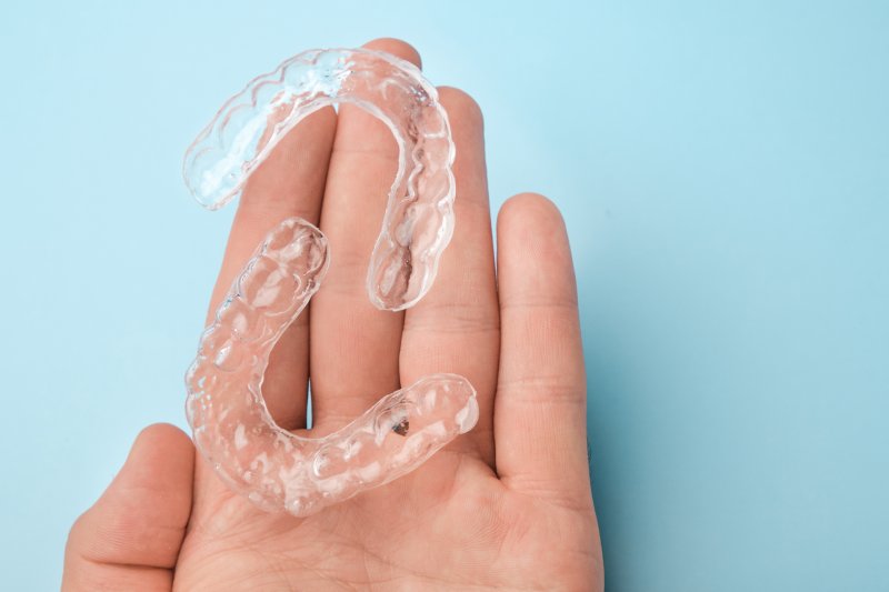 person holding two clear aligners