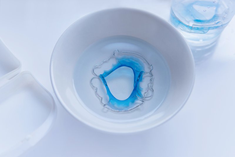 Blue retainer soaking in a bowl of water